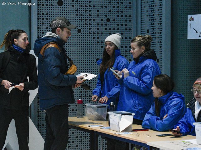 Au retrait des dossards, des bénévoles en veste bleue remettent son enveloppe à un coureur.