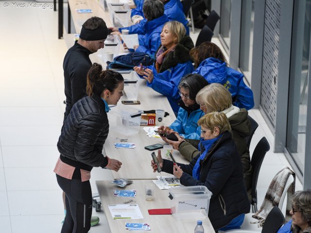 Un échange par-dessus la table entre une coureuse et les bénévoles du retrait.