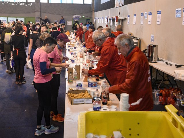 La longue table du ravitaillement d'arrivée : les bénévoles remplissent les gobelets à mesure que les coureurs se servent.