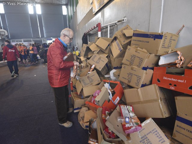 Le rangement : un bénévole devant un mur de cartons vides à plier.