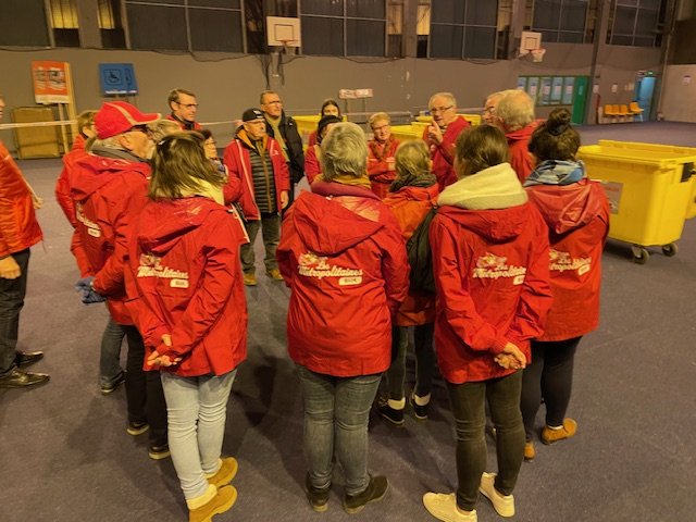 Le briefing du matin, bénévoles en veste rouge rassemblés en cercle.