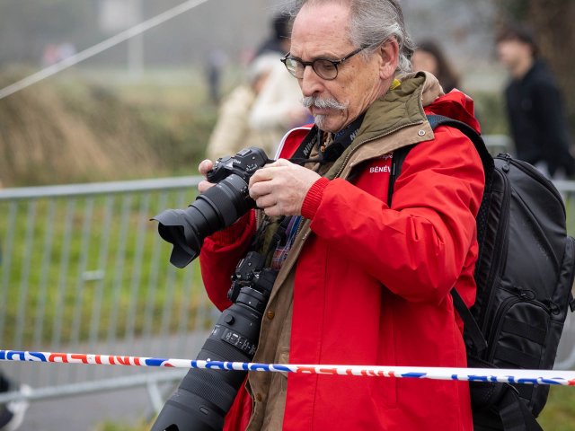 Un photographe posté derrière la rubalise, au bord du parcours.